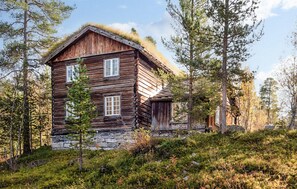 A rustic log cabin with a stone foundation, surrounded by dense forest. - Nice home in Bjorli with WiFi (Bjorli)
