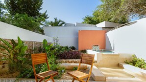 Eine Terrassenfläche mit zwei Holzstühlen, einem kleinen Pool und verschiedenen Pflanzen.