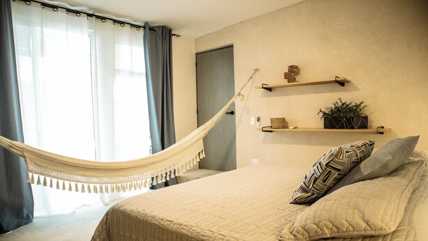 Ein Schlafzimmer mit Bett, Hängematte, Tür und Regalen mit Dekoration.