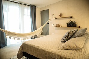 A bedroom with a bed, a hammock, a door, and shelves with decorative items. - Cozy "Casa Lucero" in Centro, Merida - 2BR (Centro)