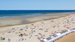 A beach with numerous sunbeds and umbrellas, a clear sky, and a calm sea. - Nice apartment in Oostende with Wi-Fi (Oostende)
