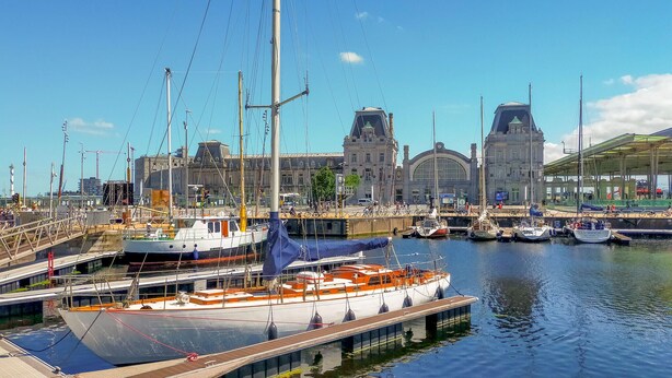 A marina with boats docked, a large building with arches in the background, and a clear blue sky. - Nice apartment in Oostende with Wi-Fi (Oostende)