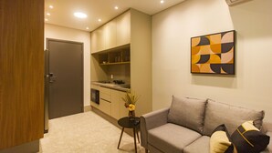 Ein modernes Wohnzimmer mit einem grauen Sofa, einem kleinen Beistelltisch und einer Vase mit Trockenpflanzen.