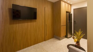 Ein modernes Zimmer mit einer Holzwand, einem Flachbildfernseher, einem Kühlschrank und einer Tür.