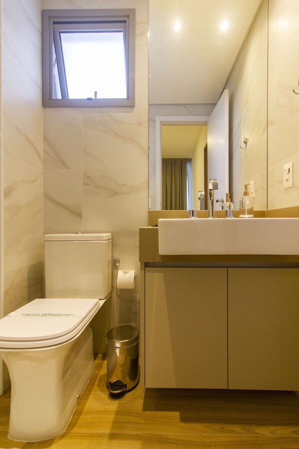 Un baño moderno con inodoro, lavamanos y espejo.