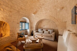 A cozy room with a stone wall, a sofa, a coffee table, and a window.