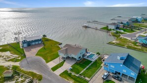 A coastal property with a large house, a swimming pool, and a pier extending into the water. - Luxury Waterfront Retreat: Pool, Fishing & 5BR, Sleeps 12 (Rockport)