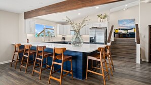 A modern kitchen with a large island, wooden bar stools, and a view of the outdoors. - Luxury Waterfront Retreat: Pool, Fishing & 5BR, Sleeps 12 (Rockport)