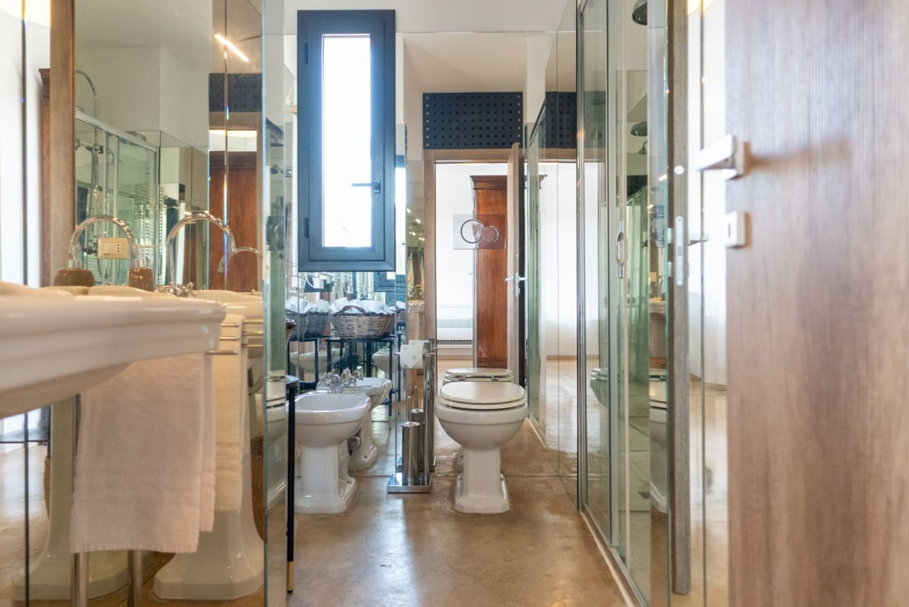 Een moderne badkamer met een douchecabine van glas, een grote spiegel en een witte wastafel.