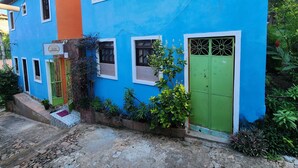 Un edificio de dos plantas con fachada azul brillante, una puerta verde y múltiples ventanales.