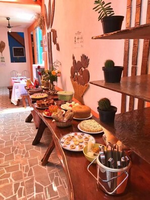 Una mesa de buffet con diferentes alimentos y un recipiente metálico con cubiertos.