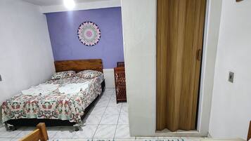 A bedroom with a bed, a wooden door, a ceiling fan, and a wall decoration.