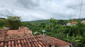 Vista de una zona residencial con tejados de tejas de arcilla, abundante vegetación y un cielo nublado.