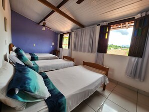 Una habitación con tres camas individuales, ventilador de techo y ventana con cortinas.