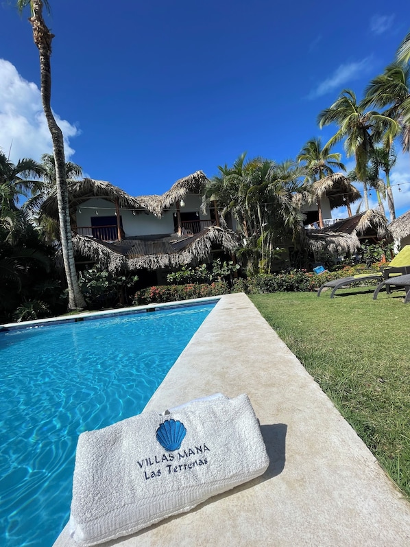 Relax by the serene pool surrounded by lush greenery and palm trees.