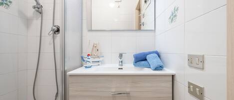 Une salle de bain moderne avec une douche, un lavabo et un miroir.