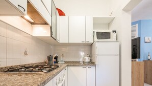 Une cuisine moderne avec des meubles blancs, un plan de travail en granit, une cuisinière, un four à micro-ondes et un réfrigérateur.