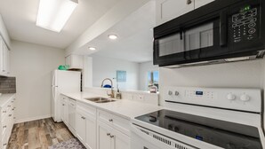 A modern kitchen with white cabinetry, a built-in microwave, and an oven. - Sunsets Over Lake Padre | Canal Home | 2 blk to beach (Corpus Christi)