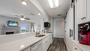 A modern kitchen with white cabinetry, a built-in microwave, and a red coffee machine. - Sunsets Over Lake Padre | Canal Home | 2 blk to beach (Corpus Christi)