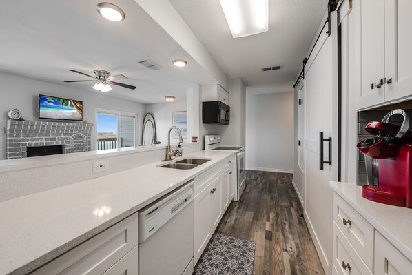 A modern kitchen with white cabinetry, a built-in microwave, and a red coffee machine.