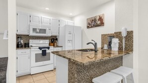 Eine moderne Küche mit weißen Schränken, einer Granit Arbeitsplatte, einem eingebauten Backofen und einem Spülbecken.
