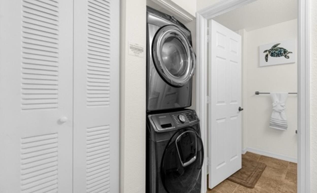 A laundry room with a front-loading washer and dryer, white doors, and a towel rack with a towel.