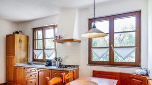 Une cuisine avec des meubles de rangement en bois, une table à manger et une fenêtre donnant sur des arbres.