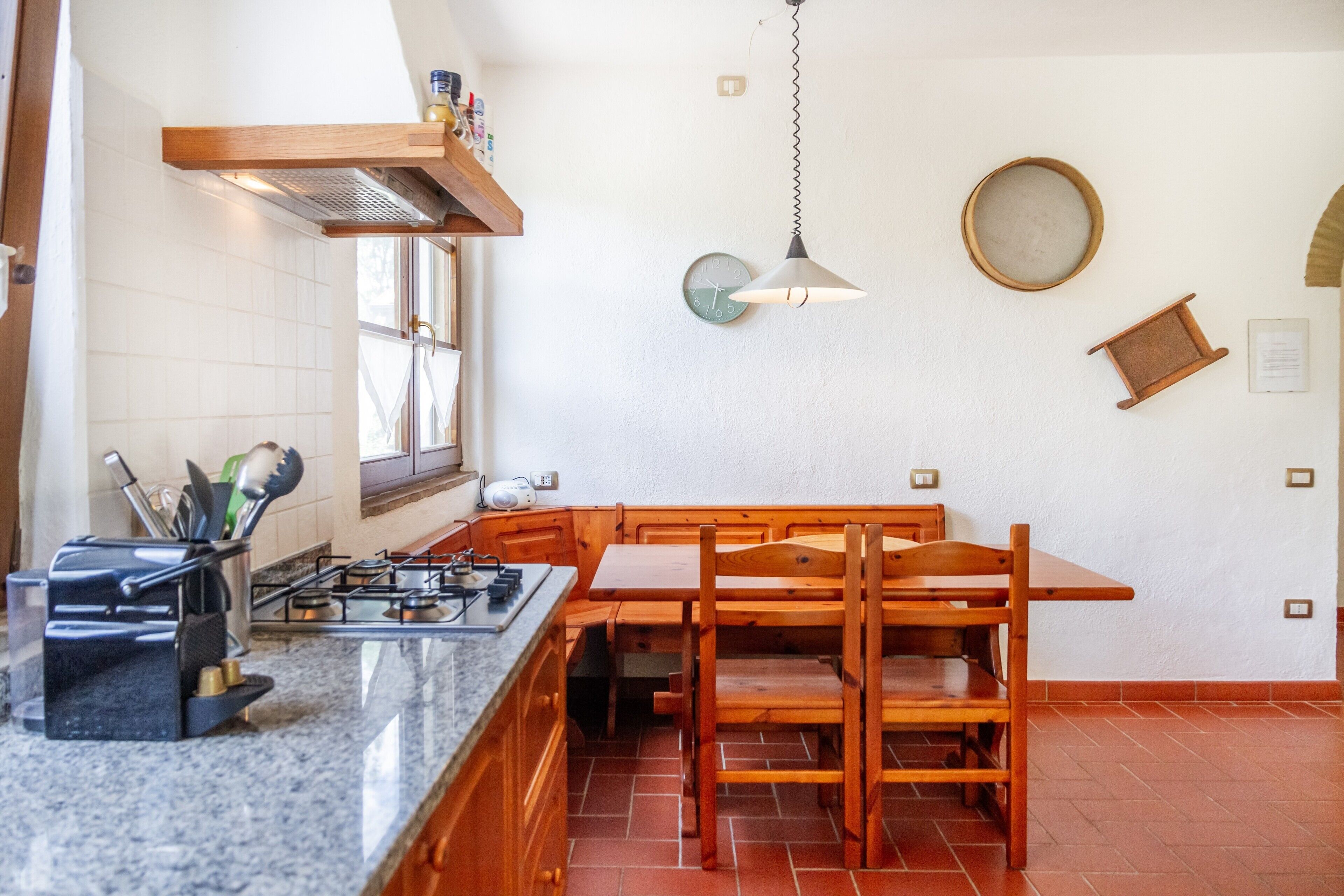 A kitchen with a wooden table, chairs, a gas stove, and a hanging light fixture.