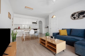 Una sala de estar moderna con un sofá azul, una mesa de centro de madera y un mueble para televisión.