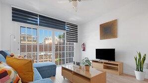 Een moderne woonkamer met een bank, een salontafel, een televisie en een potplant.