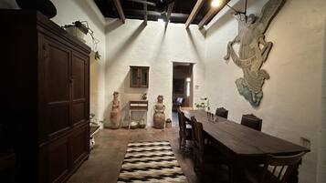 Un comedor con una mesa y sillas de madera, un tapete estampado y un adorno en la pared.