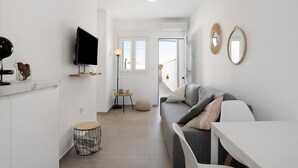 Una sala de estar moderna con un sofá, un televisor, una mesa redonda y un taburete pequeño.