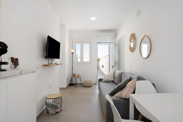 Un salon moderne avec un canapé, un téléviseur, une table ronde et un petit tabouret.