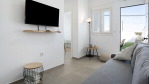 Una sala de estar moderna con un televisor de pantalla plana, un sofá, una mesita redonda y una lámpara.