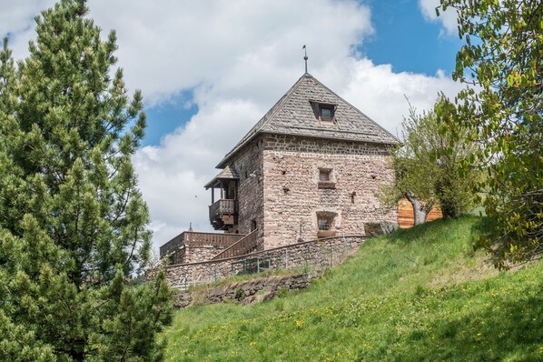 A stone building with a steep roof, a balcony, and a small window.