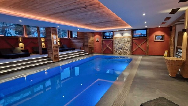 Une piscine avec des marches permettant d’y accéder, des murs en bois et un mur d’accent en pierre.