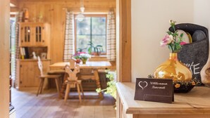 Un intérieur en bois comprenant un coin repas, un vase rempli de fleurs et une pancarte sur laquelle on peut lire « Willkommen Willkommen Willkommen ».