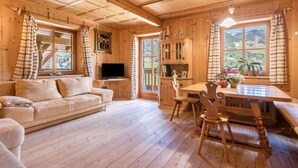 L’intérieur d’un chalet en bois comprend un canapé, un téléviseur, une table à manger, des chaises et un buffet.