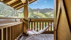 Un balcon en bois avec une chaise blanche dotée d’un coussin et un plancher en bois.