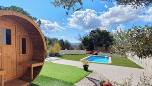 Une structure cylindrique en bois, dotée d’une porte et de fenêtres, ainsi que d’une piscine et d’une pelouse bien entretenue.