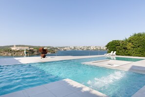 Una piscina con vistas al mar y un edificio lejano.
