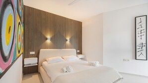 Une chambre d’hôtel moderne avec un grand lit, un mur décoratif en bois, un tableau et une œuvre d’art en noir et blanc.