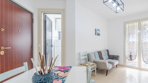 A dining area with a table set for two, a sofa, and a door leading to a balcony. - Apartment 'Casa Marsilla' with Private Terrace and Wi-Fi (Marzamemi)