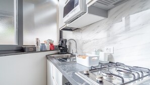 A modern kitchen with a gas stove, a coffee maker, and a window with frosted glass. - Apartment 'Casa Marsilla' with Private Terrace and Wi-Fi (Marzamemi)