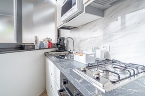 A modern kitchen with a gas stove, a coffee maker, and a window with frosted glass.