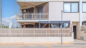 A multi-story building with a balcony, a gated entrance, and a parking area. - Apartment 'Casa Marsilla' with Private Terrace and Wi-Fi (Marzamemi)