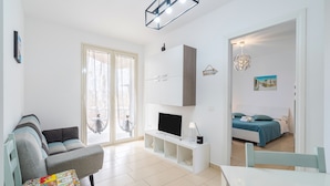 A modern living room with a sofa, TV, and a dining area. - Apartment 'Casa Marsilla' with Private Terrace and Wi-Fi (Marzamemi)