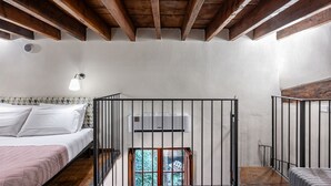A bedroom with a bed, a window, an air conditioning unit, and a wooden ceiling.