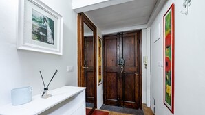 A hallway with a white counter, a framed picture, wooden double doors, and a red carpet.