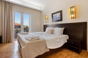 Una camera d'albergo con un letto grande, un comodino, un quadro incorniciato e vista all'esterno.